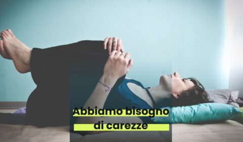 una persona (monja) stesa a terra si tiene le ginocchia tra le mani. Guarda verso l'alto. C'è una scritta: "Abbiamo bisogno di carezze"