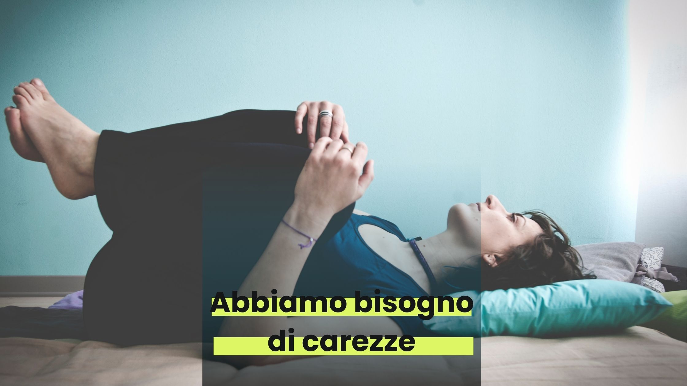 una persona (monja) stesa a terra si tiene le ginocchia tra le mani. Guarda verso l'alto. C'è una scritta: "Abbiamo bisogno di carezze"